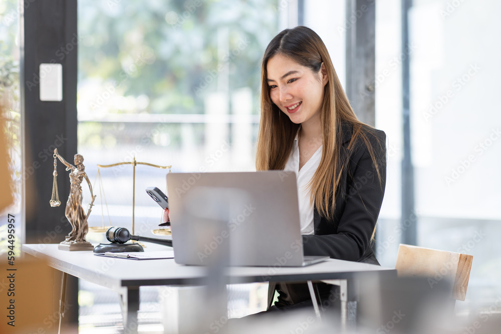 Lawyer business Asian woman office. Statue of Justice with scales and lawyer working on a laptop and using phone at workplace . Legal law, advice and justice concept.