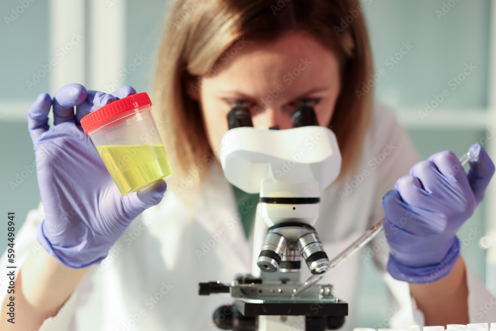 Laboratory assistant examines sample using microscope Laboratory assistant examines sample using microscope