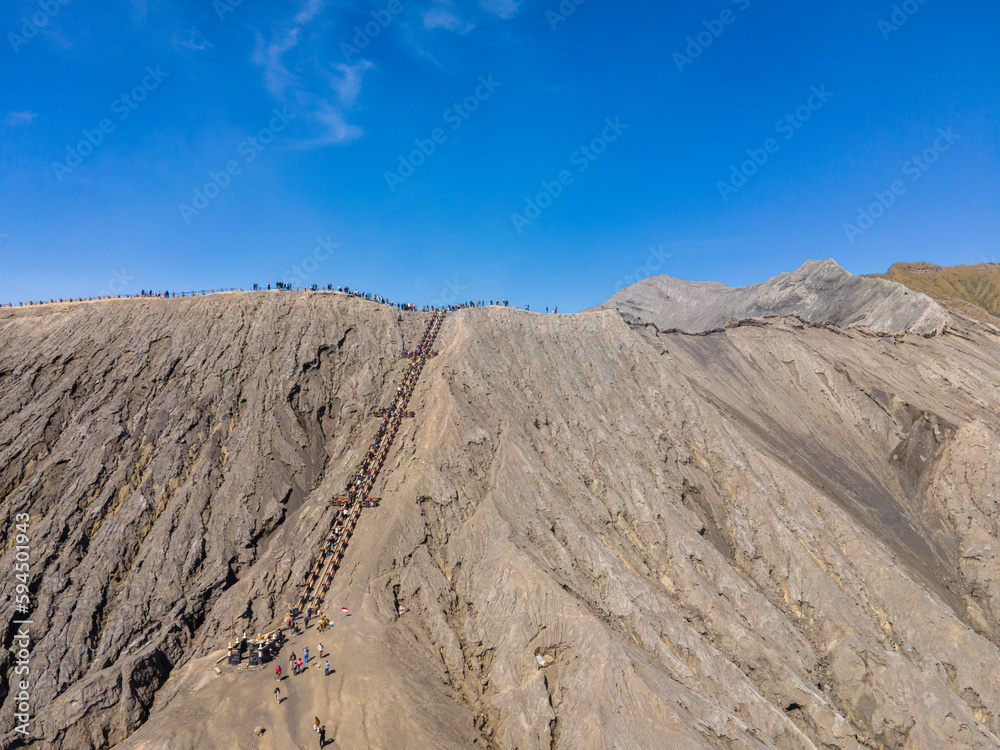 The caldera and the peak of Mount Bromo are photographed from a height. It looks like the tourists are climbing and enjoying the peak. Mt.Bromo is a popular tourist destination in East Java, Indonesia