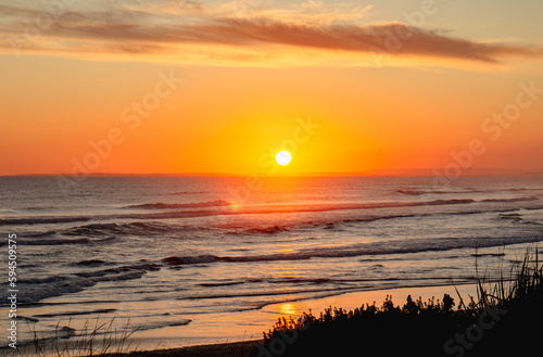Long exposure of bright orange sunset over the tropical sea and sky with clouds. Beautiful sunset blue summer.
