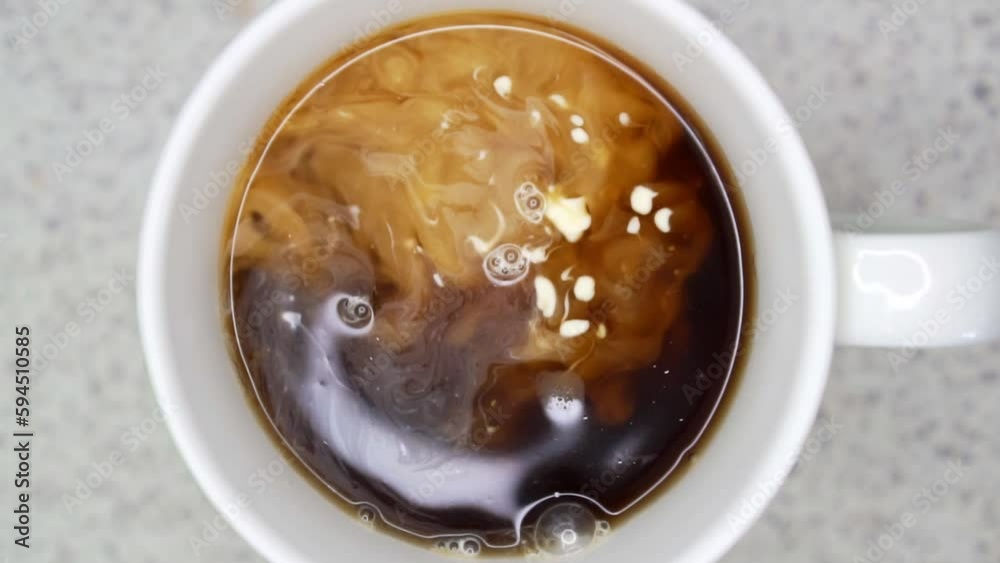 Black Coffee and thick cream swirling in mug, slow motion, close up Black Coffee and thick cream swirling in mug, slow motion, close up