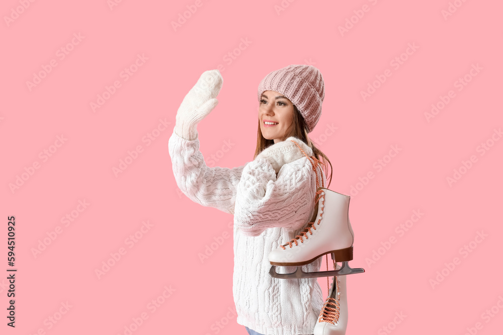 Pretty young woman with ice skates waving hand on pink background Pretty young woman with ice skates waving hand on pink background