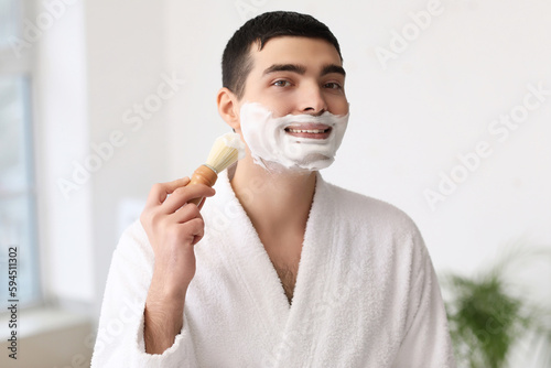 Young man shaving in bathroom