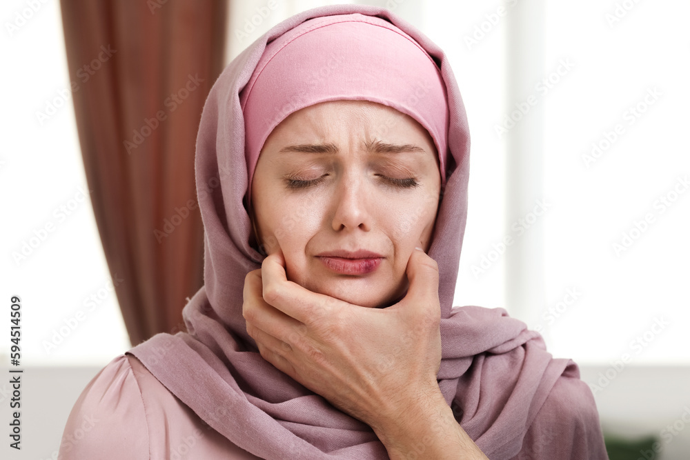 Muslim man holding bruised woman by face at home, closeup. Domestic violence concept