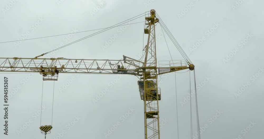 Snowfall and Construction: Zooming in on a Tower Crane Against a Cloudy Sky Snowfall and Construction: Zooming in on a Tower Crane Against a Cloudy Sky