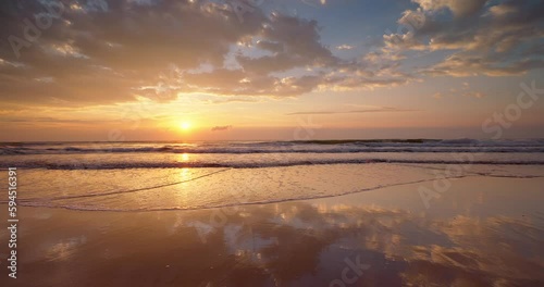 Tropical beach sunrise with golden sun rays over the sand and sea