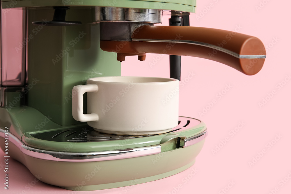 Modern coffee machine with cup on pink background, closeup Modern coffee machine with cup on pink background, closeup