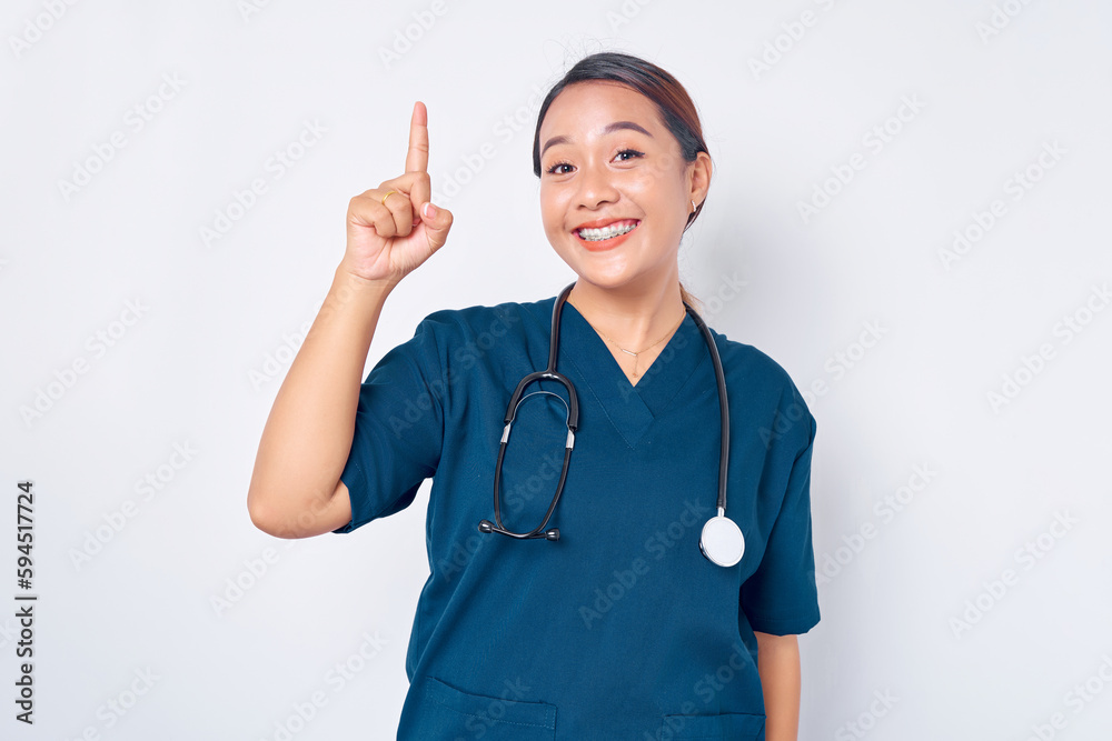 Cheerful young Asian female professional nurse working wearing a blue uniform having creative ideas and solutions while pointing fingers up isolated on white background. Healthcare medicine concept Cheerful young Asian female professional nurse working wearing a blue uniform having creative ideas and solutions while pointing fingers up isolated on white background. Healthcare medicine concept