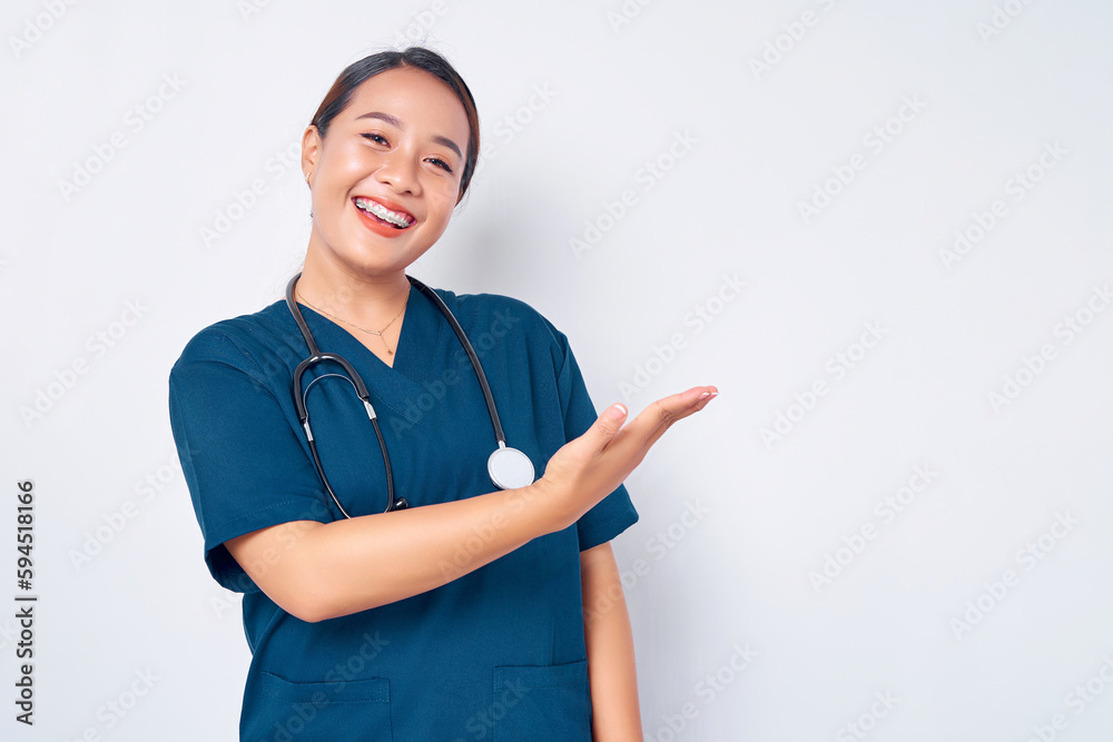 Cheerful young Asian female professional nurse working wearing a blue uniform shows empty space on a palm while presenting a product isolated on white background. Healthcare medicine concept Cheerful young Asian female professional nurse working wearing a blue uniform shows empty space on a palm while presenting a product isolated on white background. Healthcare medicine concept