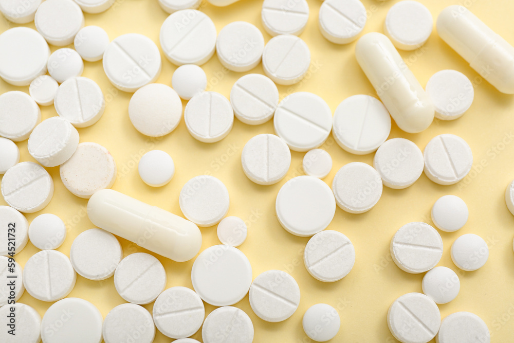 White pills on yellow background, closeup White pills on yellow background, closeup