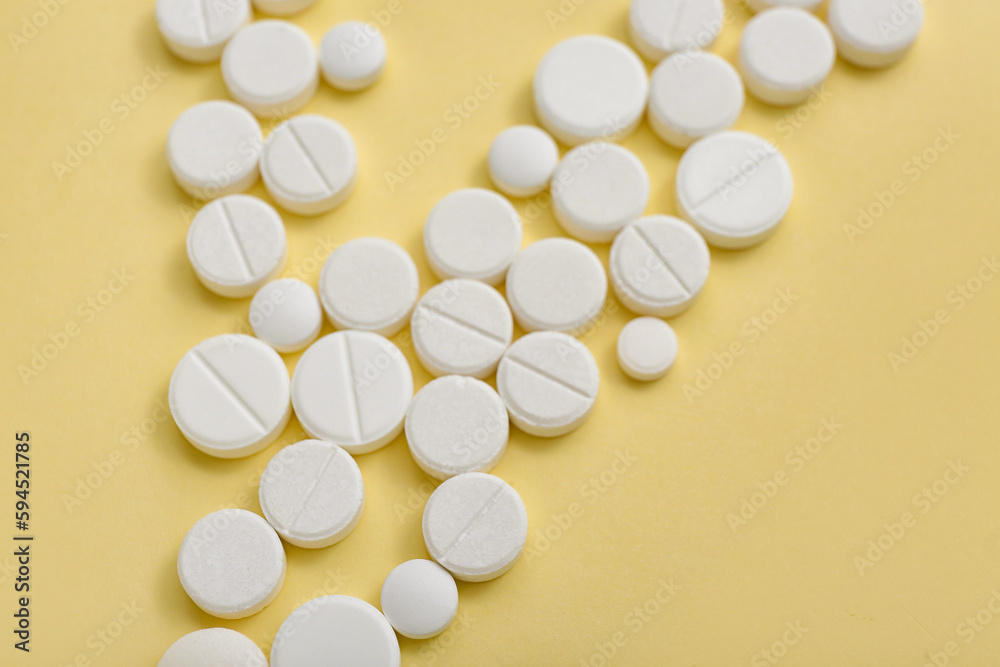 White pills on yellow background, closeup White pills on yellow background, closeup