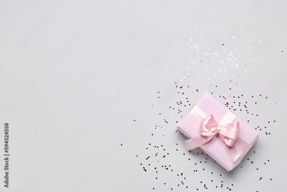 Gift box with beautiful bow and confetti on grey background Gift box with beautiful bow and confetti on grey background
