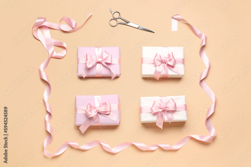 Gift boxes with beautiful bows, ribbon and scissors on beige background