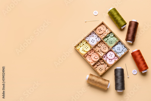 Composition with different buttons, thread spools and ball pins on color background