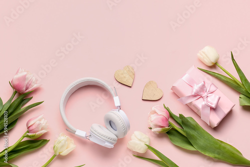 Composition with modern headphones, gift box and beautiful tulip flowers on pink background