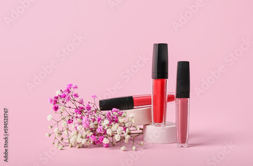 Decorative plaster podium, lip gloss and gypsophila flowers on pink background