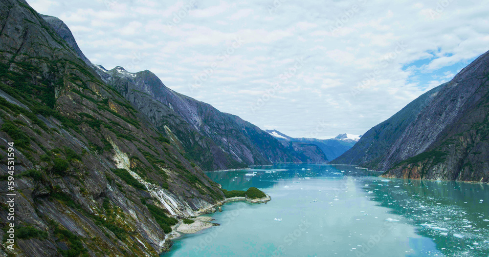 Rocks, melting ice, glaciers, rivers, forests and mountains seen from above. Stunning aerial views of Alaska in summer from a drone.