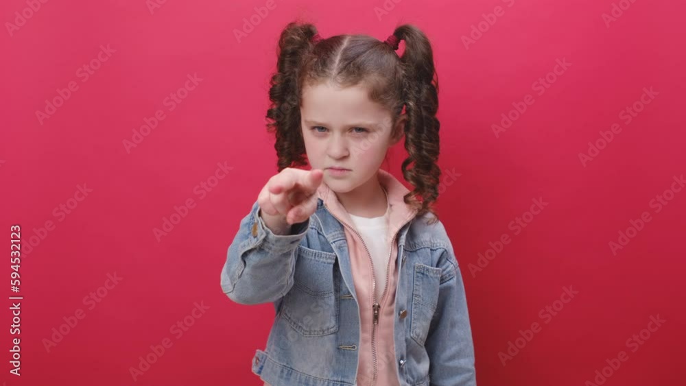 Portrait of serious preteen girl kid pointing at her eyes and camera, show I am watching you gesture, spying on someone, see, posing isolated on red color background wall in studio. I am watching you Portrait of serious preteen girl kid pointing at her eyes and camera, show I am watching you gesture, spying on someone, see, posing isolated on red color background wall in studio. I am watching you