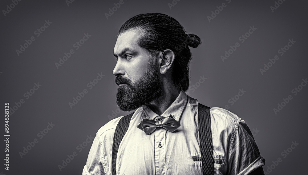 Fototapeta premium Closeup of a gentleman his bowtie. Beard man in bow tie and suspenders. Portrait of handsome bearded man in white shirt and bow tie, suspenders. Black and white