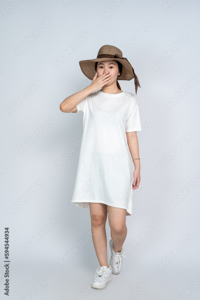 A young asian woman doing a pose while wearing a white blank shirt dress and a hat A young asian woman doing a pose while wearing a white blank shirt dress and a hat