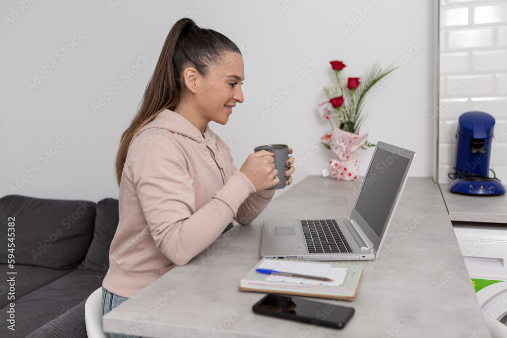 Cheerful woman with coffee having video call on laptop Cheerful woman with coffee having video call on laptop