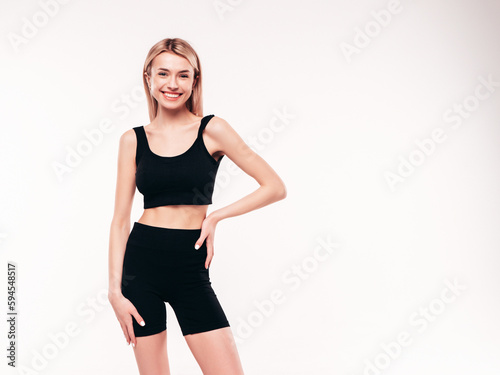 Young beautiful smiling blond female in black cycling shorts clothes. Sexy carefree woman posing on white background in studio. Positive model having fun indoors. Cheerful and happy