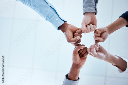 Business people, fist circle and teamwork in low angle, team building and trust in office. Solidarity, huddle and group or staff of men and women with hands together for unity, synergy or cooperation