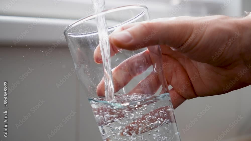 Man pouring clean tap drinking water into the clean glass on sunny day.