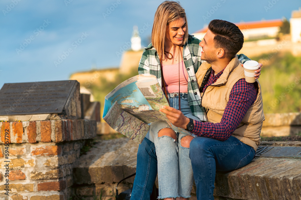 a couple in love, a girlfriend sits on a boyfriend's lap while they read a map and take a break from sightseeing