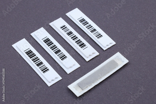 Magnetic AM label with barcode: the necessary protection even for small products. Plastic White Barcode Soft Tags on gray background. Retail security. photo