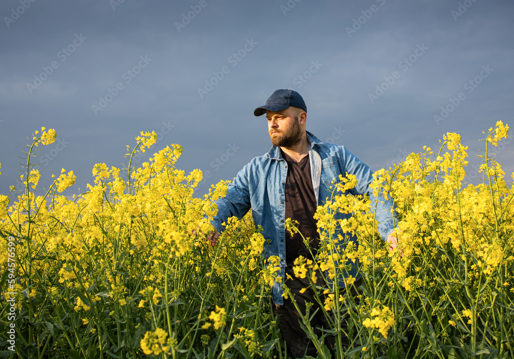 Young farmer in field of blooming rapeseed