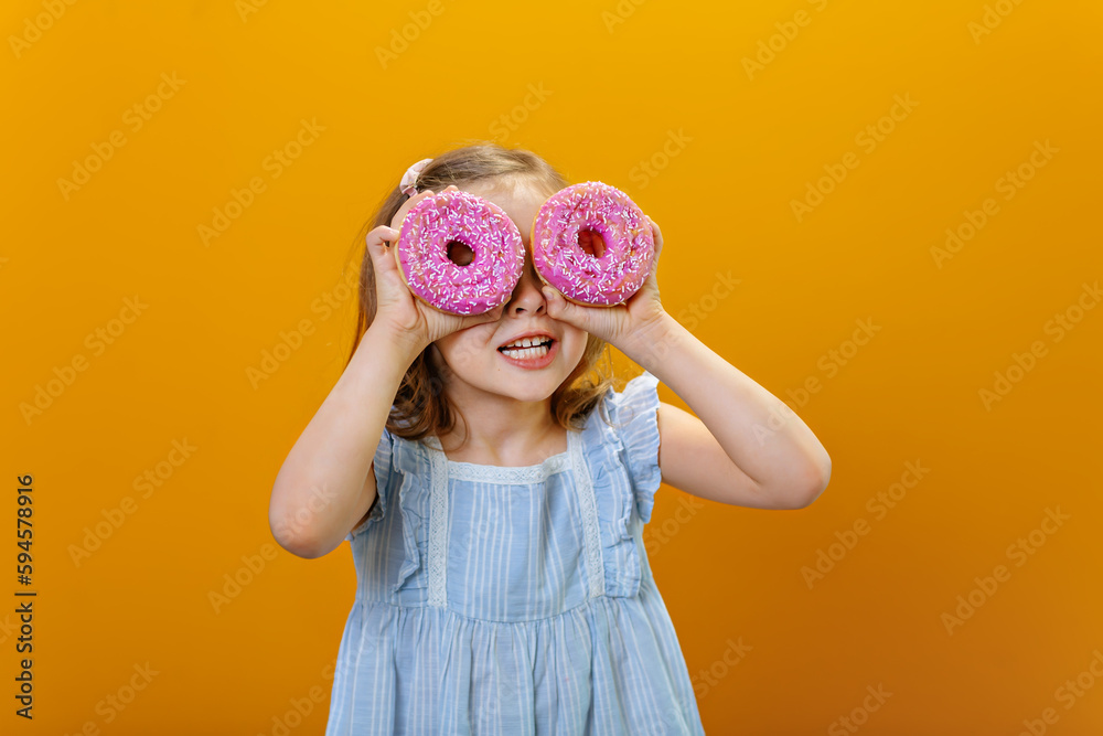 a girl holding two doughnuts in front of her eyes and looking through them as if through rose-colored glasses.