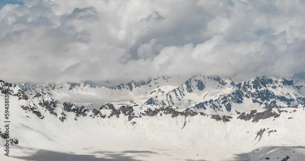 Air flight through mountain clouds over beautiful snow-capped peaks of mountains and glaciers.