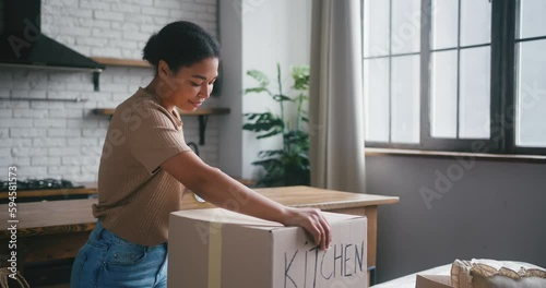 Hispanic woman prepares cardboard boxes for moving in flat