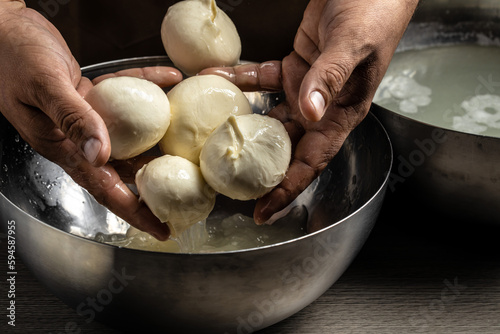 A man working in a small family creamery is processing the final steps of making a cheese. Italian hard cheese silano or caciocavallo, mozzarella