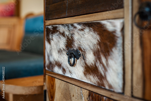 Detailed view of a cupboard with drawers in the kitchen. One drawer element is covered with cowhide.