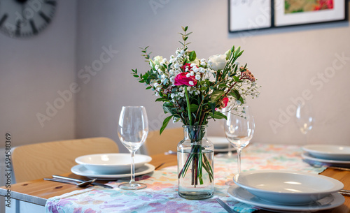 Laid table with glasses and plates, a flower vase with spring flowers is on the table
