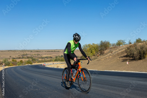 Cyclist riding bicycle on road against clear sky