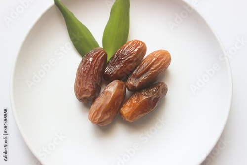 Dried dates on a white plate for Ramadan on a white background
