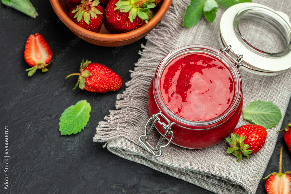 Strawberry jam in the glass jar with a spoon at dark table. top view Strawberry jam in the glass jar with a spoon at dark table. top view