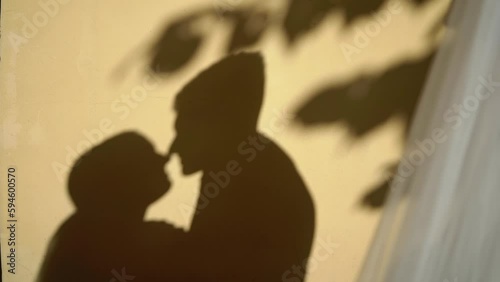 Shadow on yellow wall of building outdoors of couple in love looking to each other and kissing. Man and woman, sensual. Lovely family - bride and groom at the wedding.