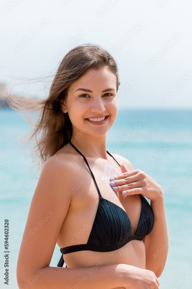 Young attractive woman is protecting her skin on the breast with sunblock at the sunny beach Young attractive woman is protecting her skin on the breast with sunblock at the sunny beach