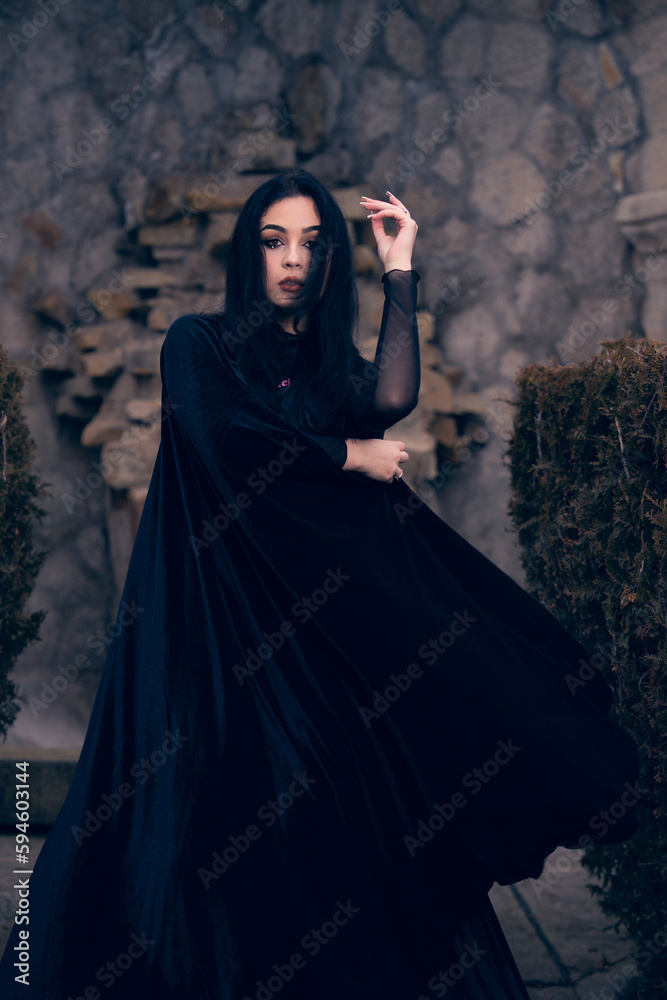 a woman in a black outfit and boots posing for a picture in front of a stone wall and a stone archway, a character portrait, gothic art