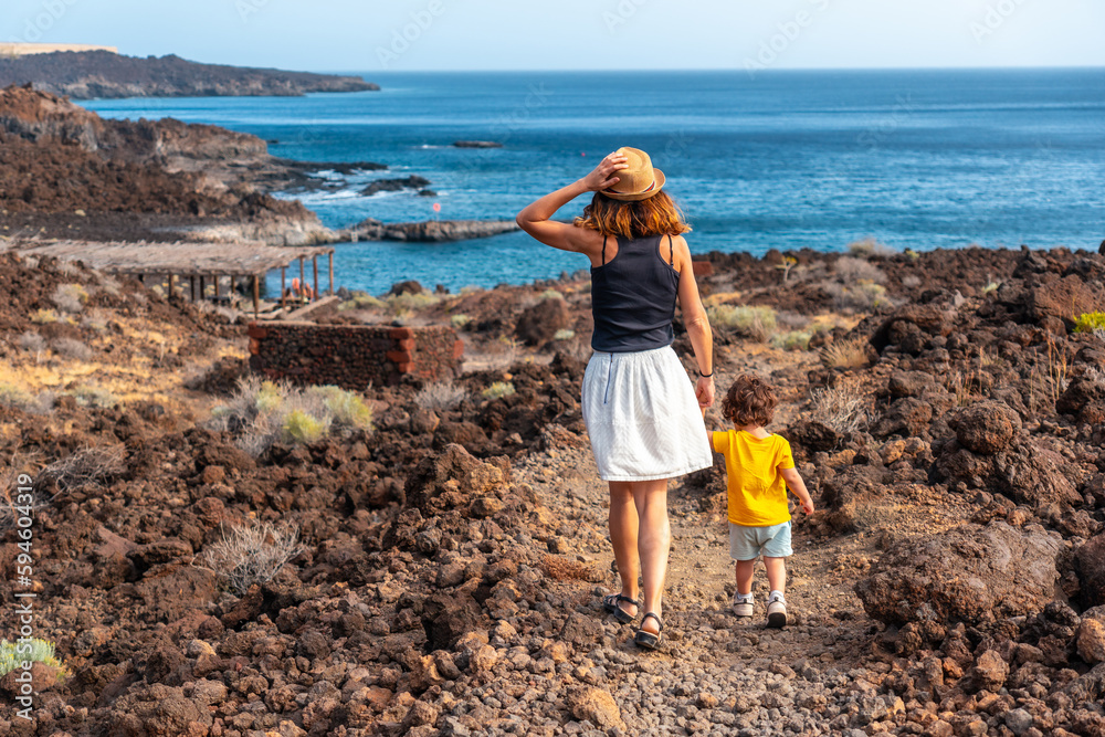 Mother and son on vacation walking on a path along the beach of Tacoron on El Hierro, Canary Islands Mother and son on vacation walking on a path along the beach of Tacoron on El Hierro, Canary Islands
