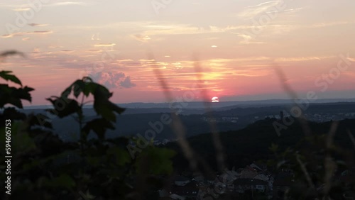 timelapse of the sunset over Forbach, France. The camera captures the changing colors of the sky as the sun sets behind the Schlossberg Castle photo