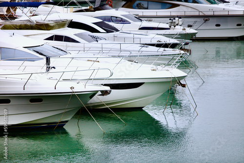 Yachts and speed boats at harbor. Yachts moored in the port. Ocean Coast pier. High class lifestyle. Yachting. Expensive toys. Sea ​​transport. Nautical. Yachting sport. Expensive yachts at the pier. © ST-art