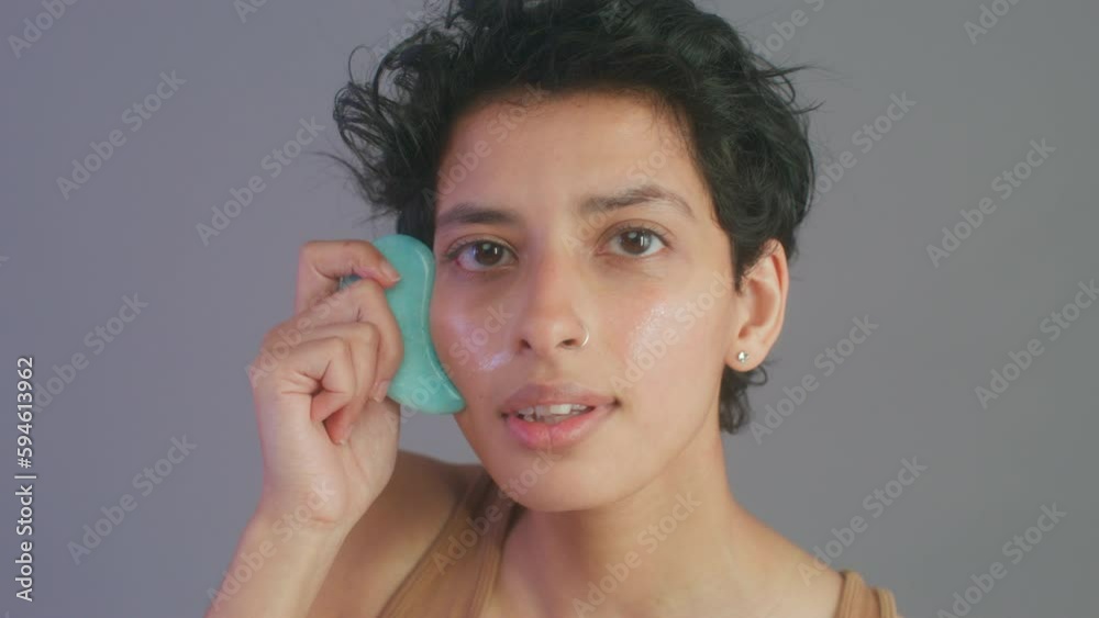 CU Studio portrait of woman massaging face with gua sha CU Studio portrait of woman massaging face with gua sha