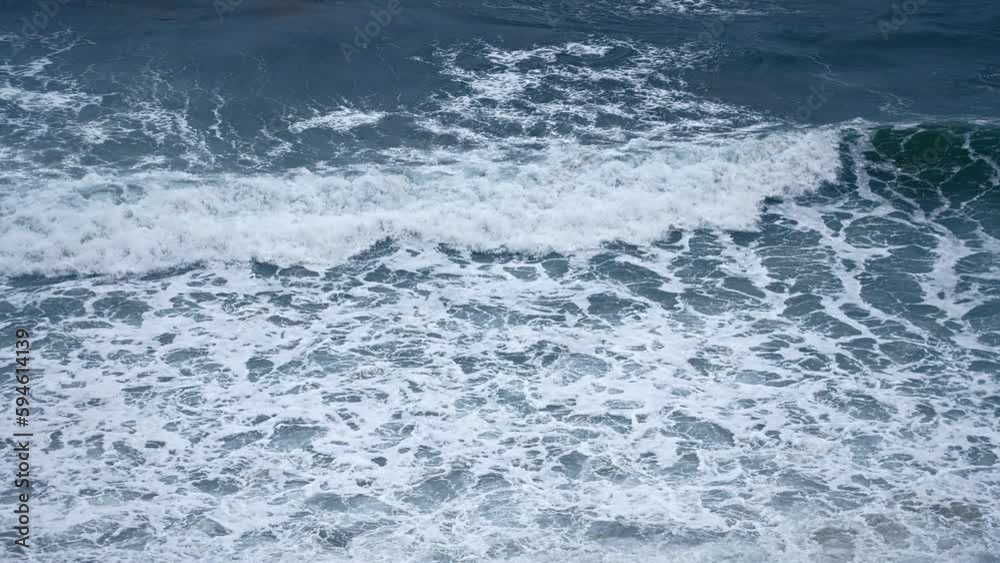 Slow motion Top view. Sea surf during a storm. Huge storm waves roll onto the shore covered with white foam. Boundless and powerful water element. Slow motion Top view. Sea surf during a storm. Huge storm waves roll onto the shore covered with white foam. Boundless and powerful water element.