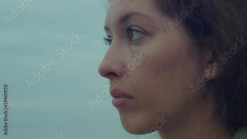 Young woman crying on the beach, looking sadly at the horizon close-up shot
