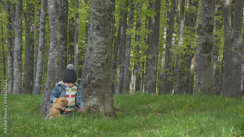 Little kid with teddy bear in the forest, falls down then rise up and continue walking Little kid with teddy bear in the forest, falls down then rise up and continue walking